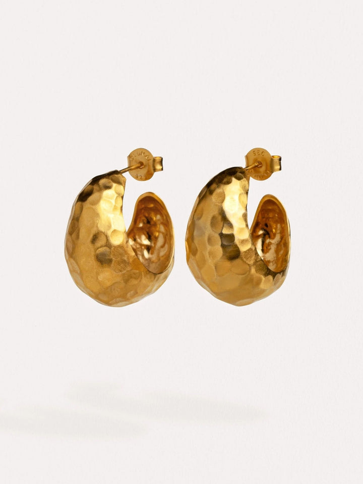 Hammered gold hoop earrings on white background