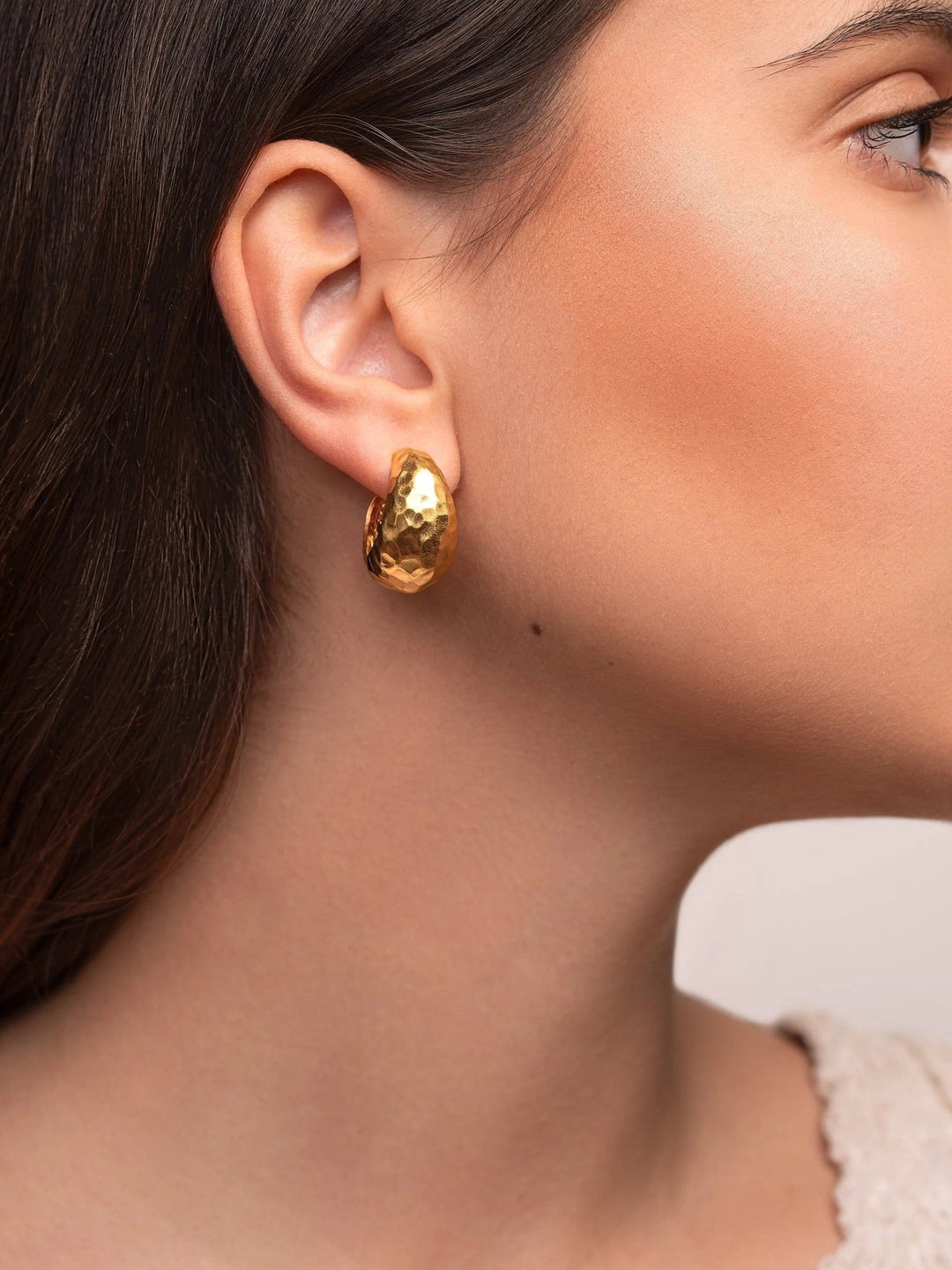 Close-up of woman wearing gold hammered hoop earrings