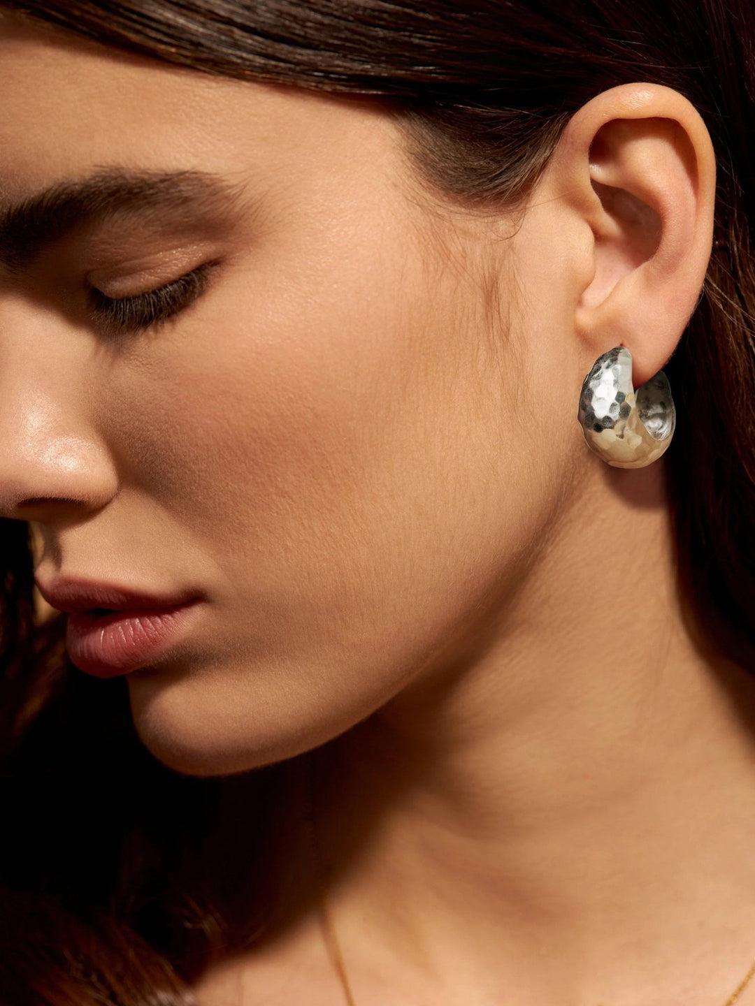 Woman wearing silver hoop earrings with a textured finish