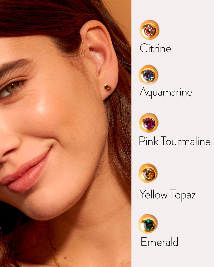 Smiling woman wearing a small gold stud earring, with gemstone options displayed on screen.